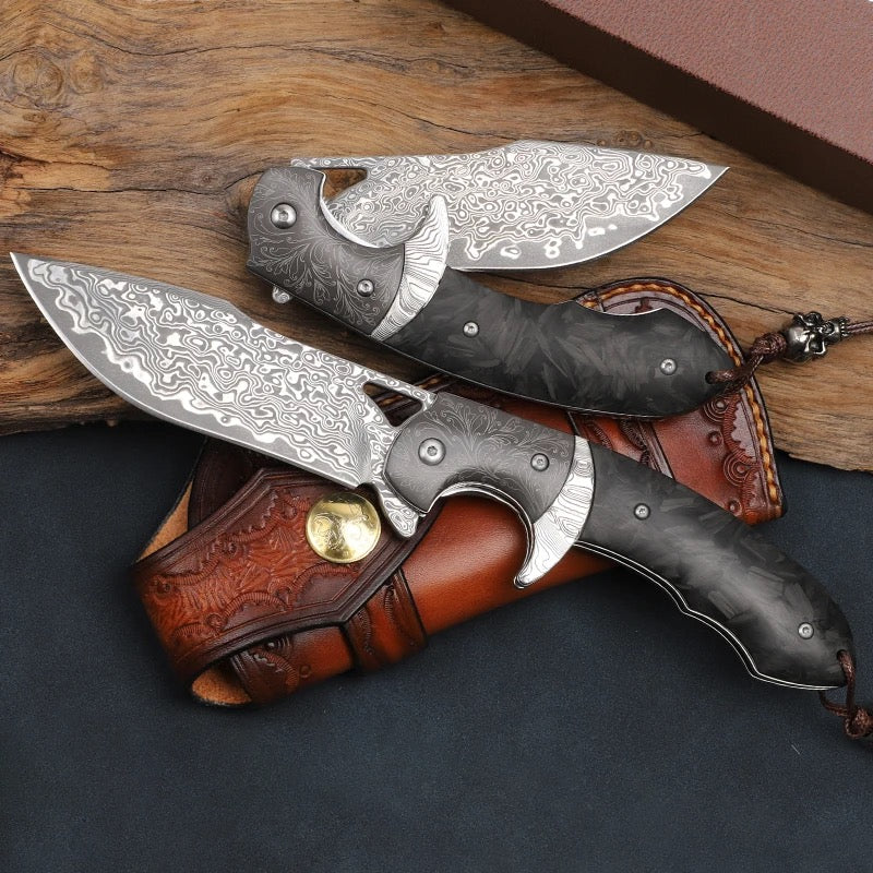 Handmade folding knife with a detailed Damascus steel blade and a dark, textured handle. The knife is paired with a custom, intricately designed leather sheath featuring decorative stitching and a brass button closure.